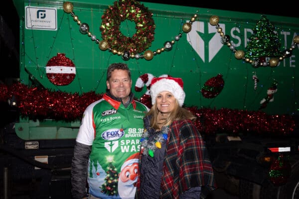 Two Spartan Waste team members smiling in front of their holiday parade float in downtown Spartanburg.